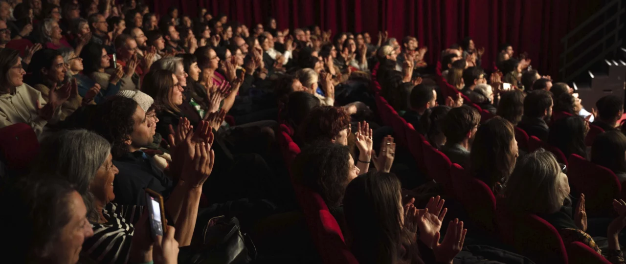 Des gens dans une salle sombre aplaudissent